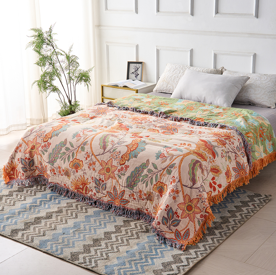Floral cotton throw spread over a bed with contrasting reverse visible