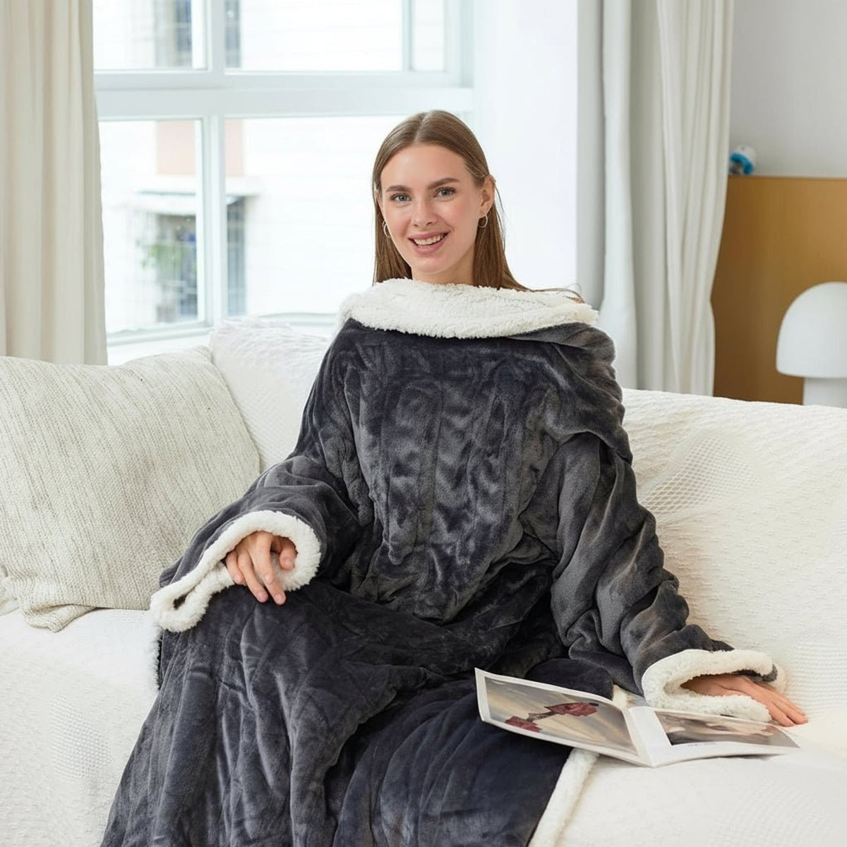 Grey wearable heated blanket with white sherpa trim worn on a sofa