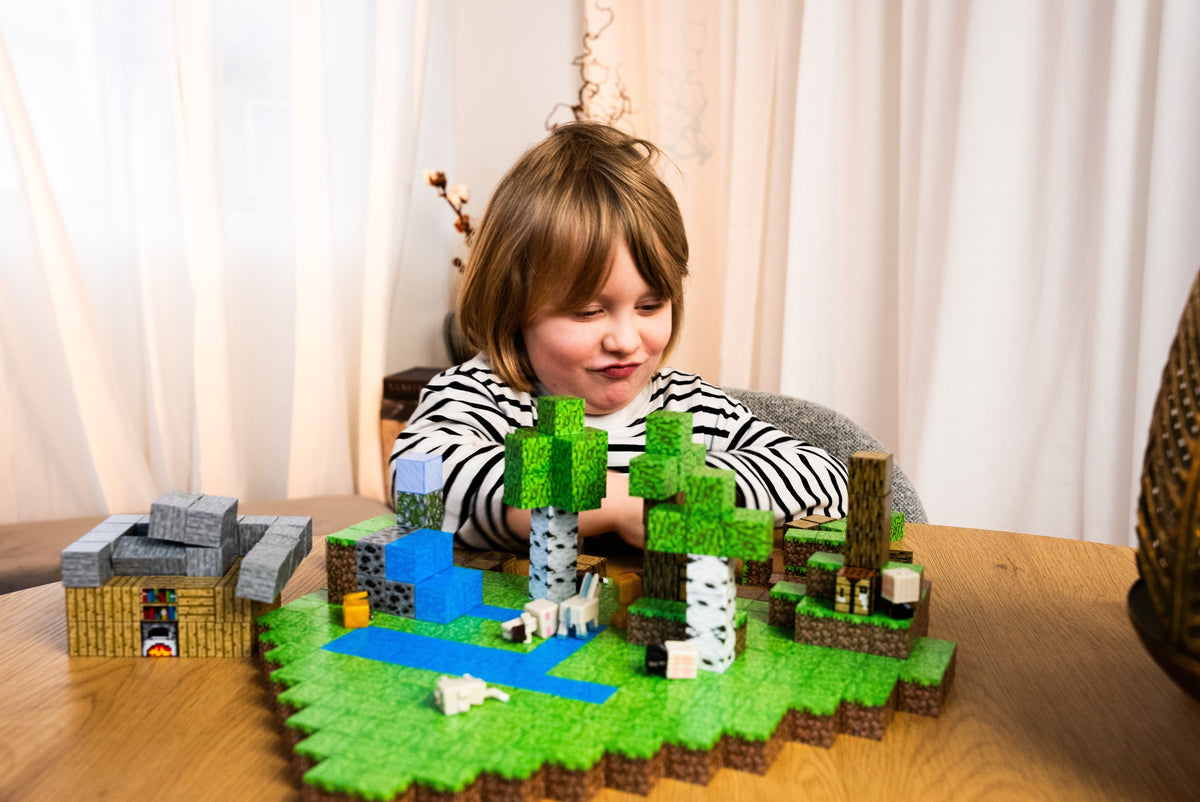 Child beside a large magnetic building block landscape