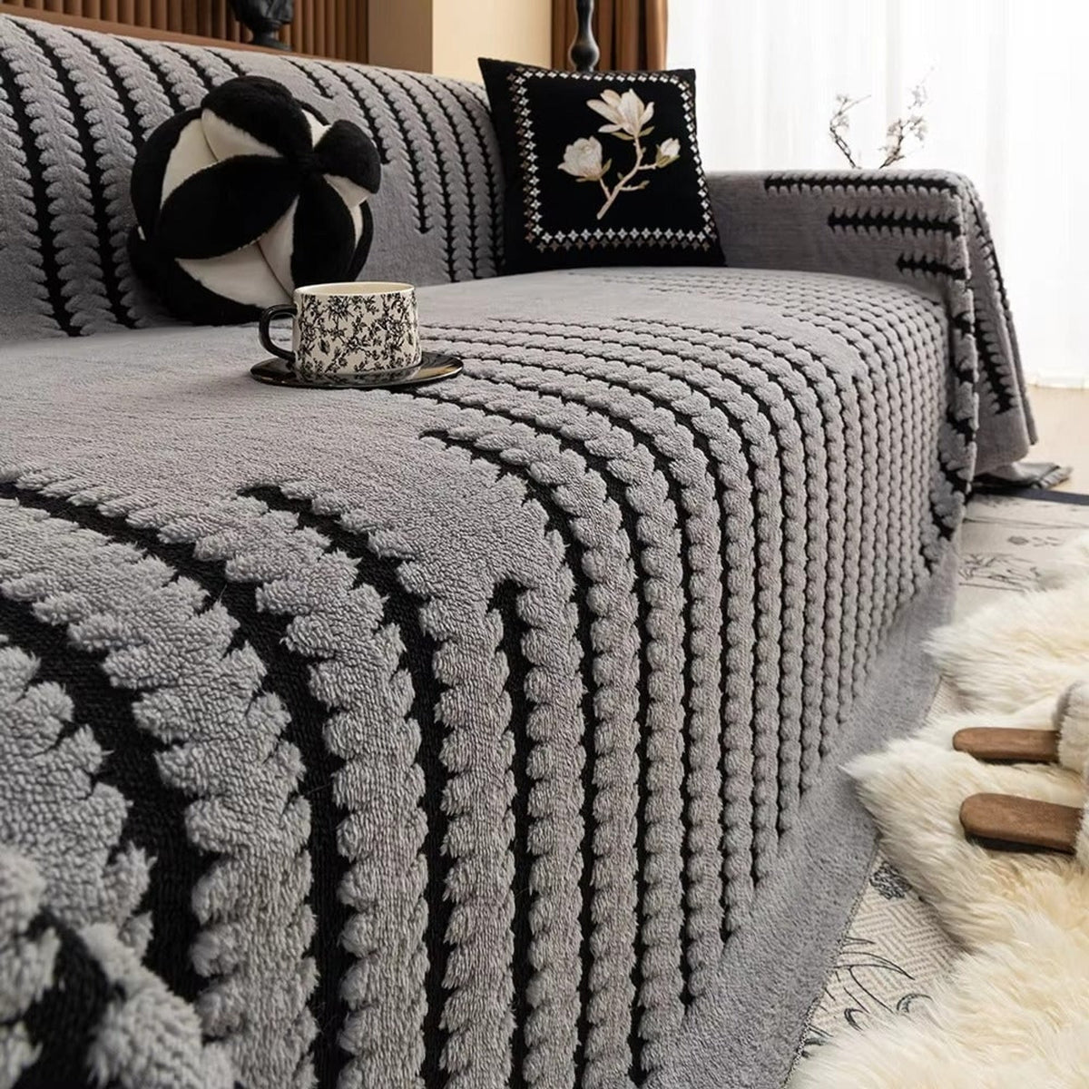 Grey tufted blanket with contrasting black stripes on a sofa