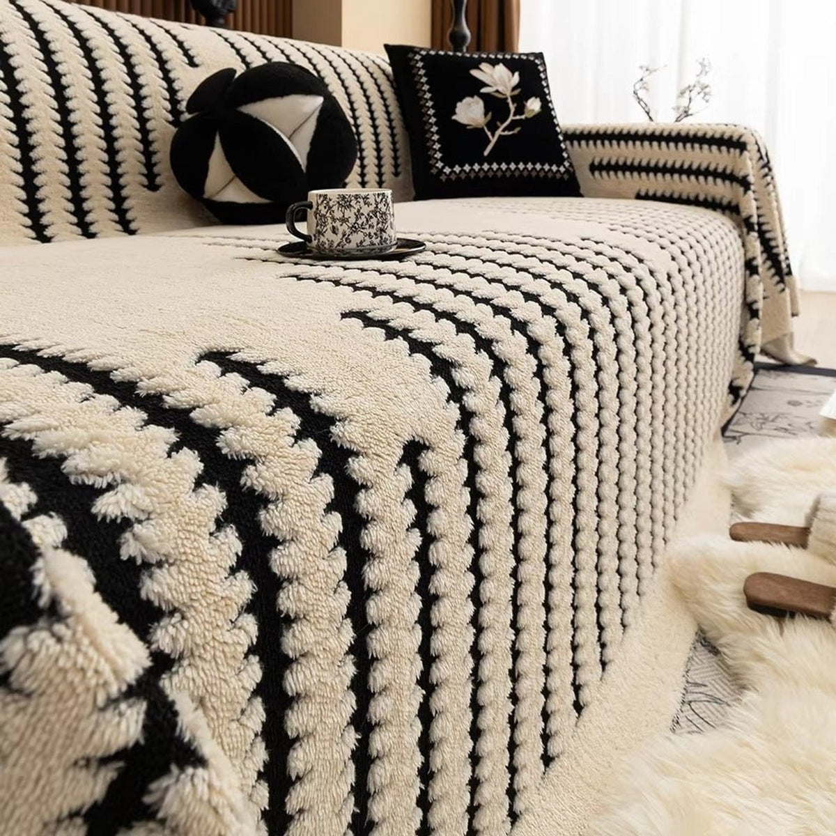 Ivory tufted blanket with contrasting black stripes on a sofa