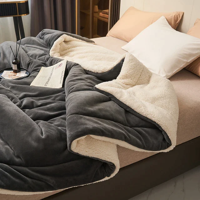 Black fleece blanket with cream sherpa lining on a bed