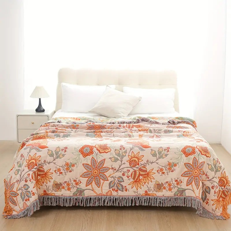 Floral throw blanket with tassel edging on a bed