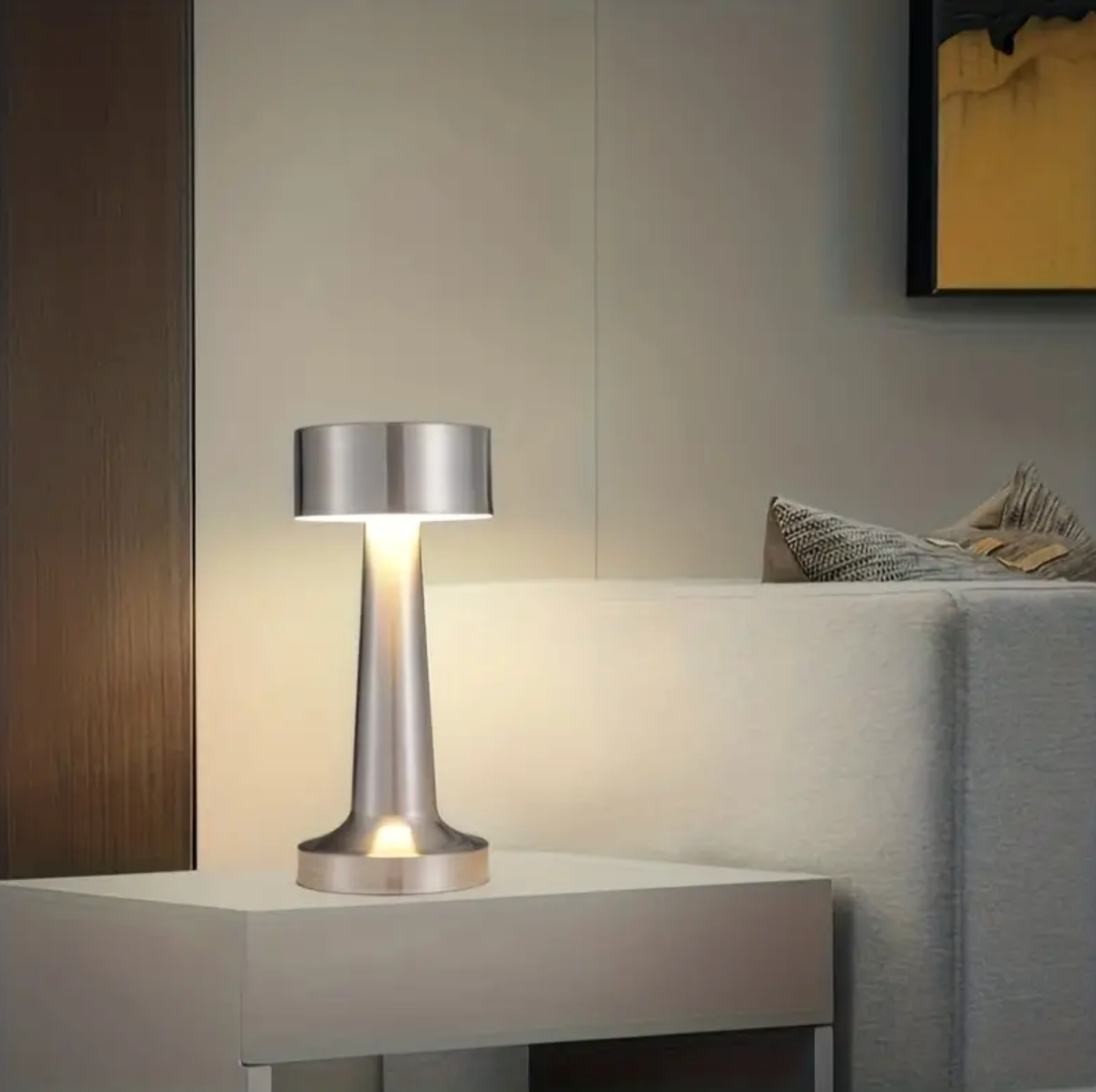 Modern silver table lamp on a nightstand with a neutral background