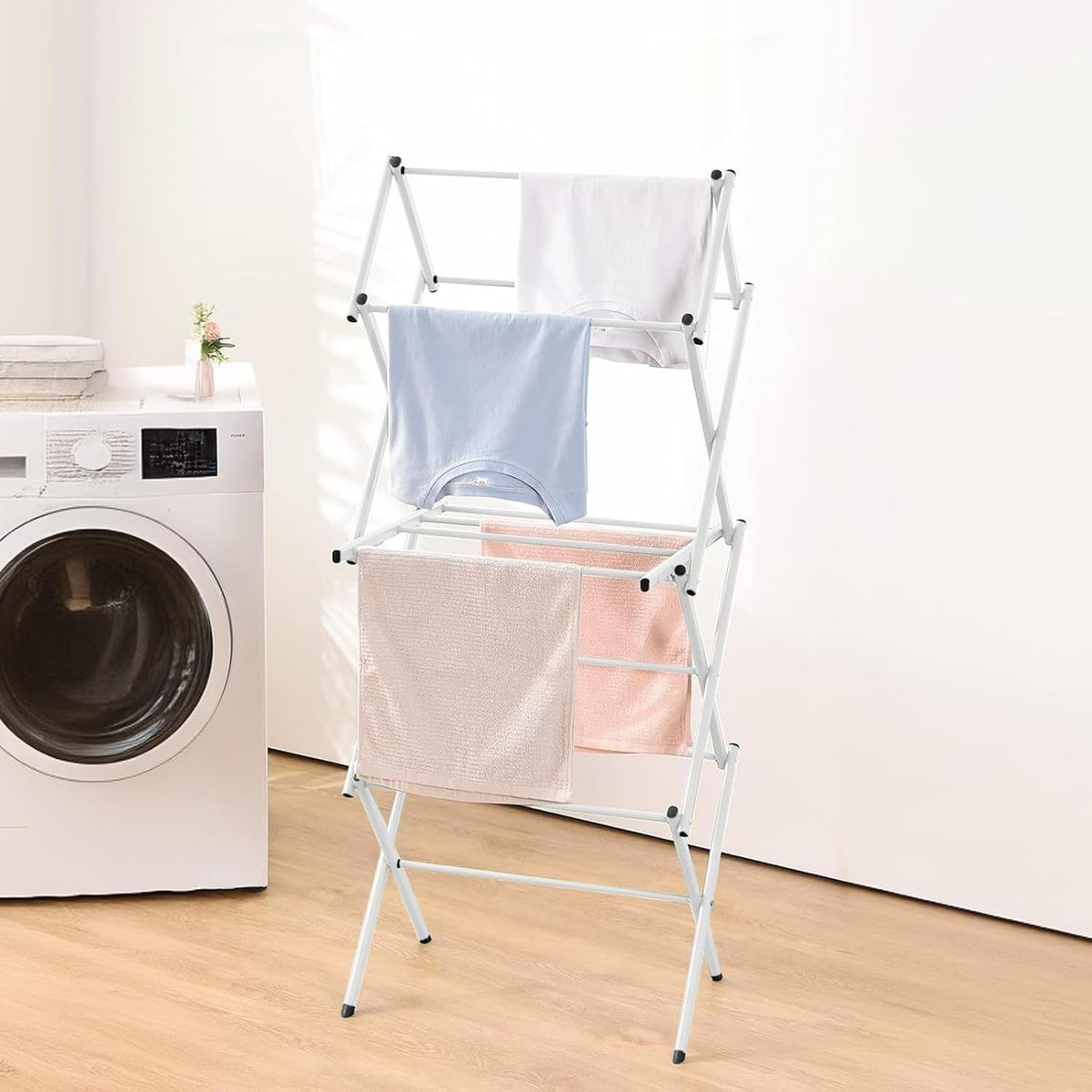 White accordion drying rack holding clothing and towels