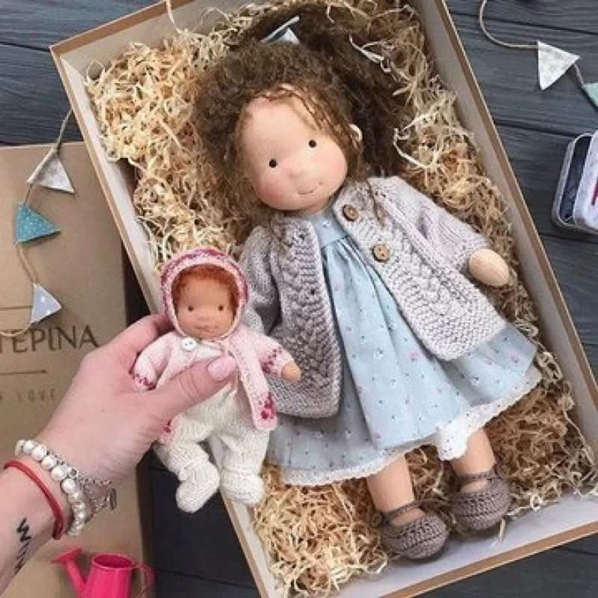 Brown-haired cloth doll in blue dress and grey cardigan