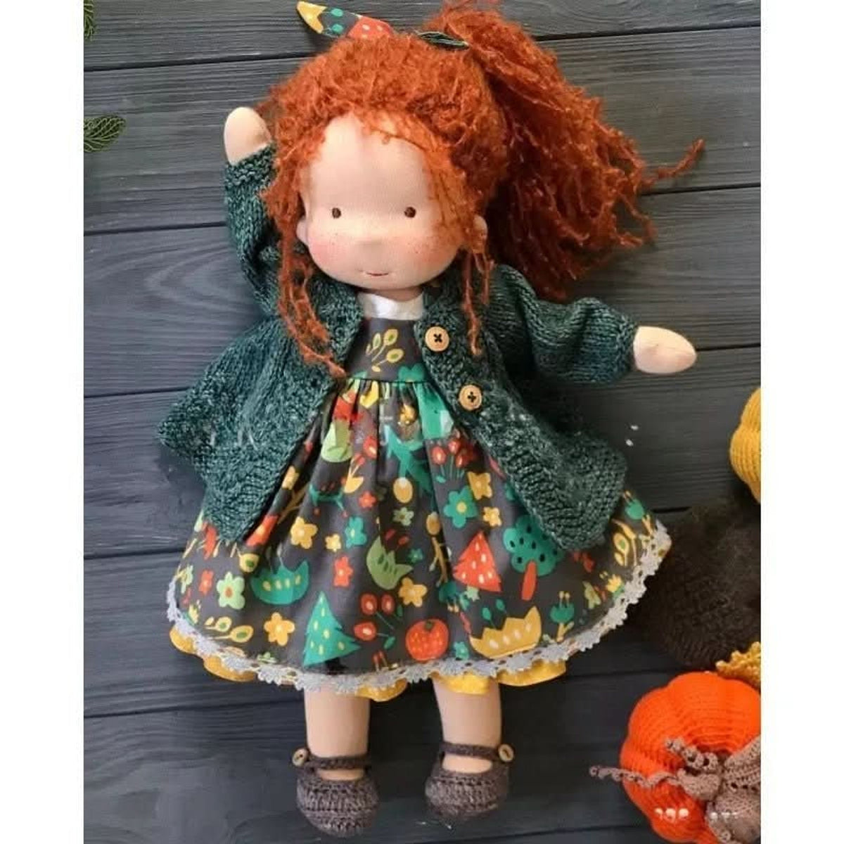 Red-haired cloth doll in green jacket and cat-patterned dress