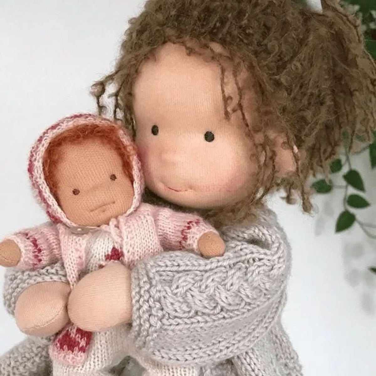 Brown-haired cloth doll shown holding a small cloth baby doll