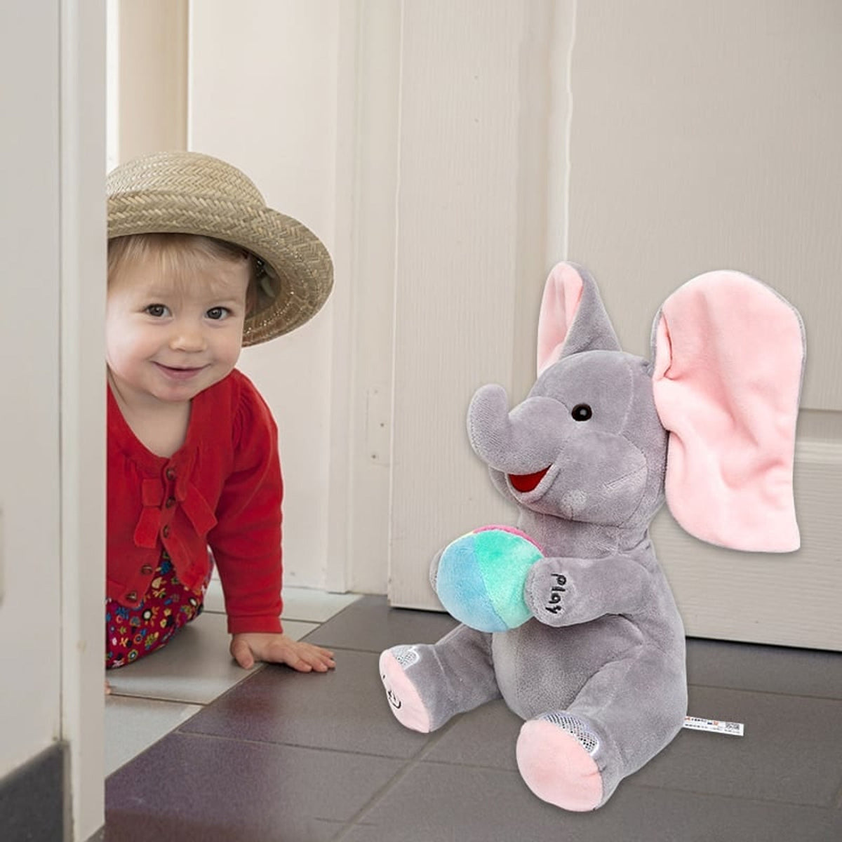 Toddler beside a seated elephant plush toy