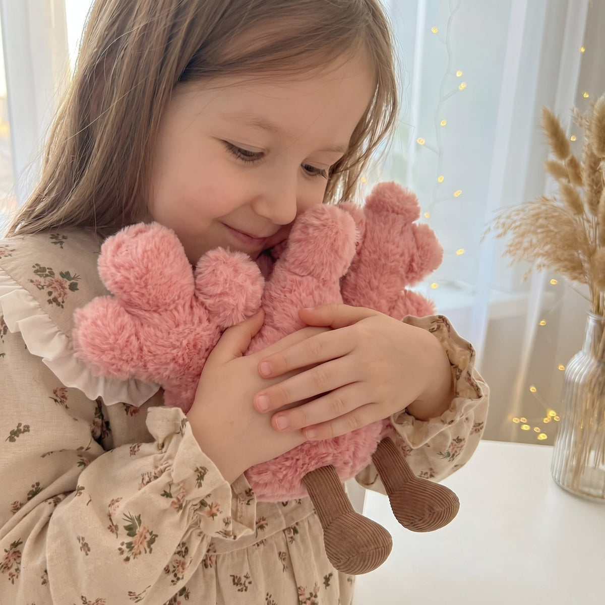Child holding a pink branching coral plush toy