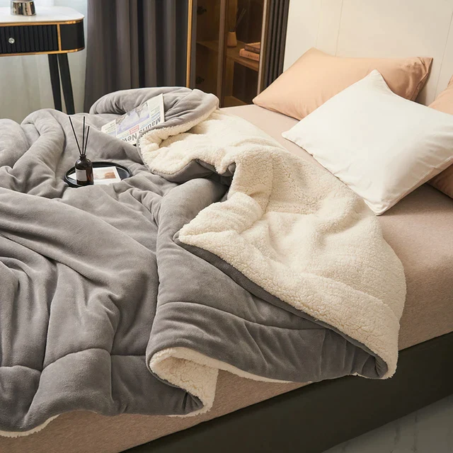 Grey fleece blanket with cream sherpa lining on a bed